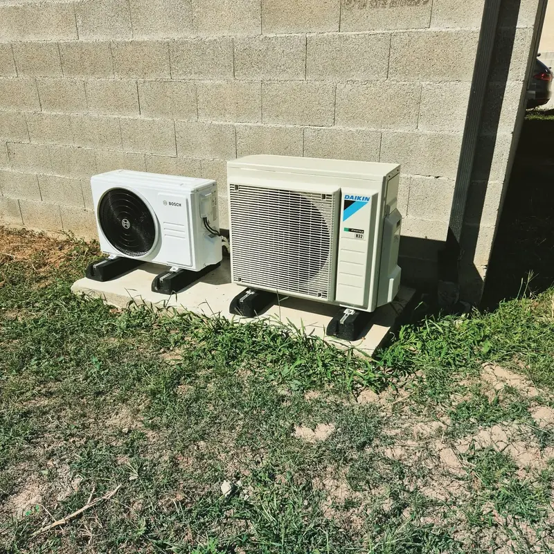 Deux groupes extérieurs Daikin et Bosch posés sur des plots au pied d'une maison